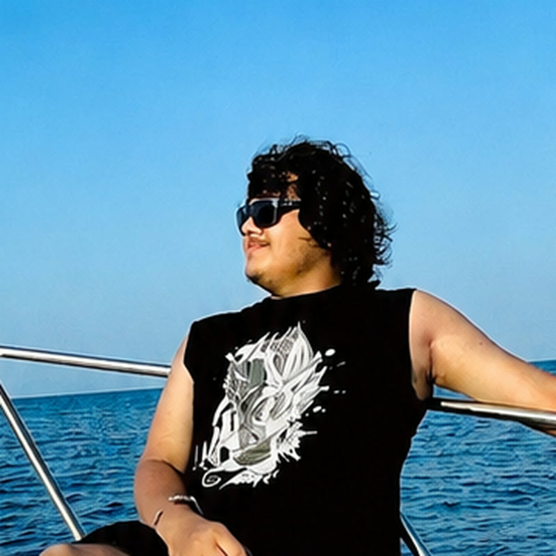 Kartik Avadhani sitting on a boat with the sea behind him